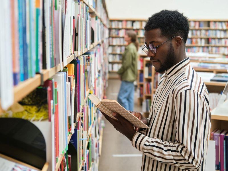Male student choosing a book in his university library