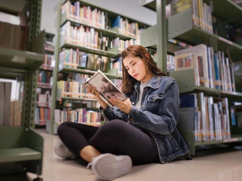 Female student reading a book in the university library