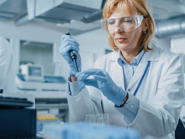 Woman researcher with pipette wearing protective glasses