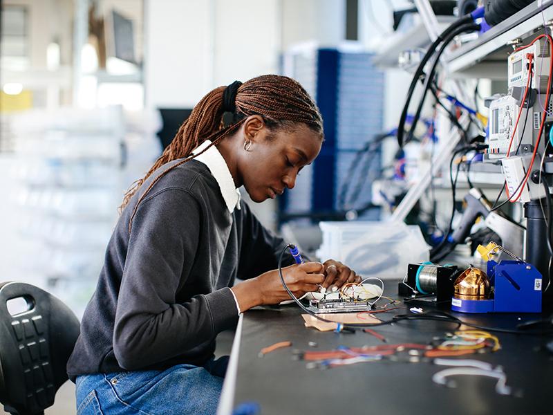 Black female student works on a circuit board