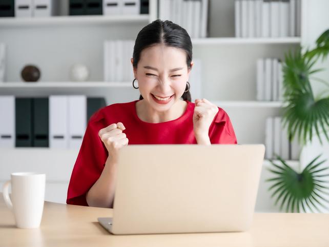 Young Asian woman in red top happy in front of laptop