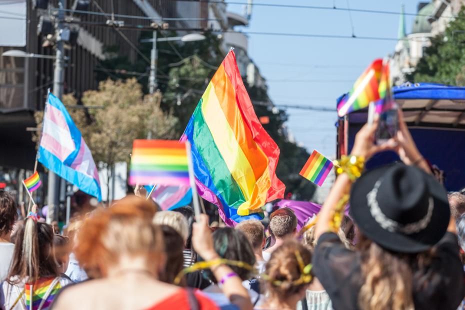 A Pride march with people waving rainbow flags