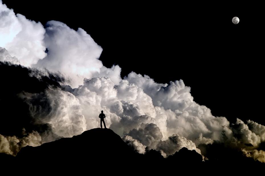 A man silhouetted against dramatic storm clouds.