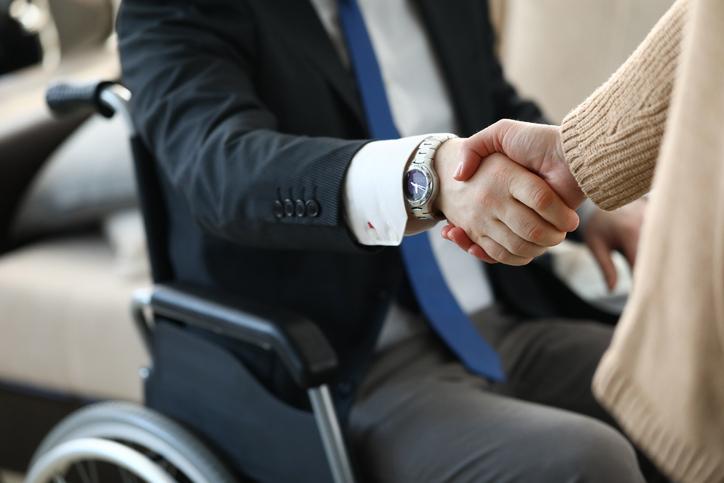 Man in wheelchair and woman shaking hands