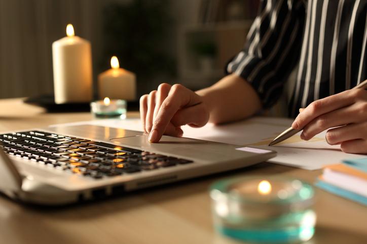 A hand uses a laptop trackpad as candles burn in the background