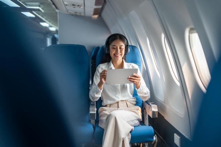 A woman uses a tablet device while sitting in an aeroplane seat