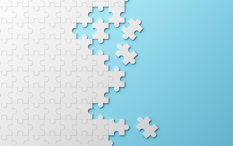 A white half-completed jigsaw puzzle against a blue background