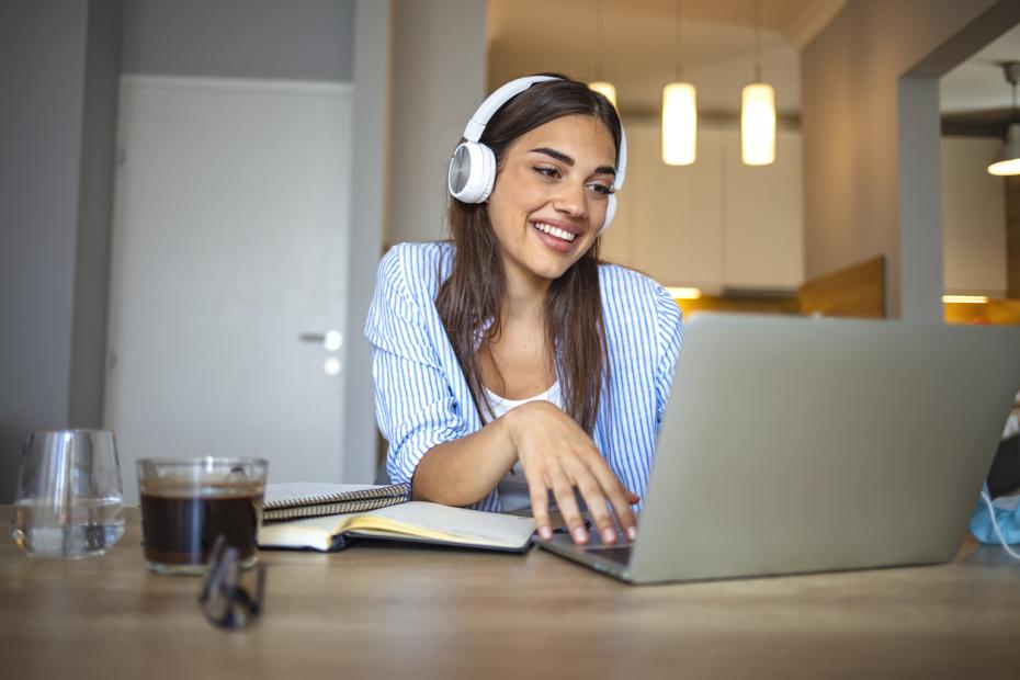 Young female student studying at her laptop with headphones on