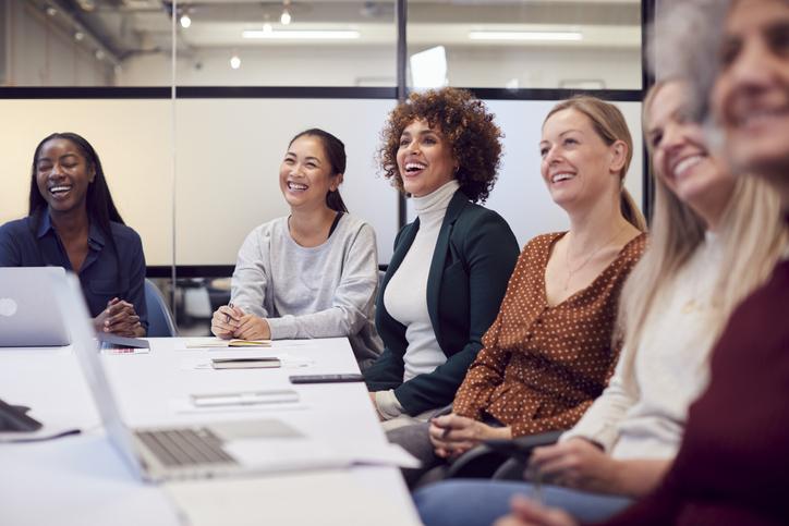 A group of women sit round a meeting room table