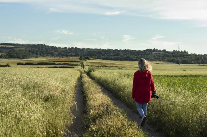 A woman walks along a path in a grassy meadow
