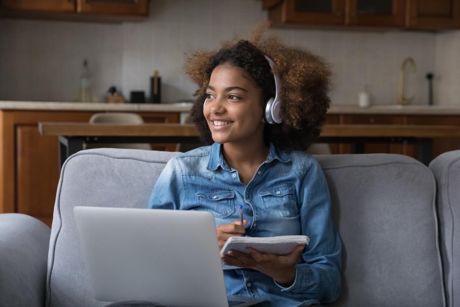 Student on a laptop listening with headphones at home