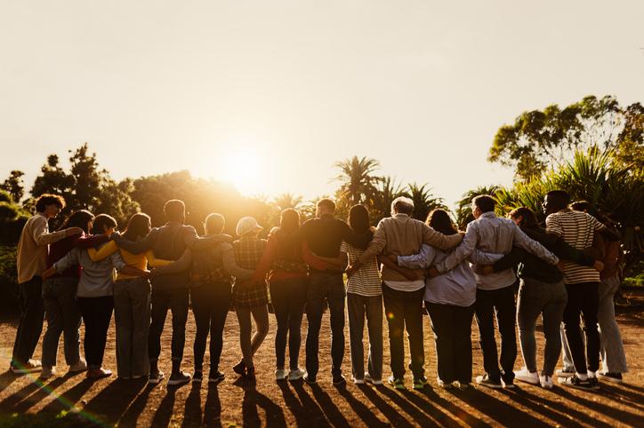 A group of people link arms as the sun sets