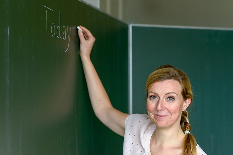 College teacher writing class agenda on blackboard