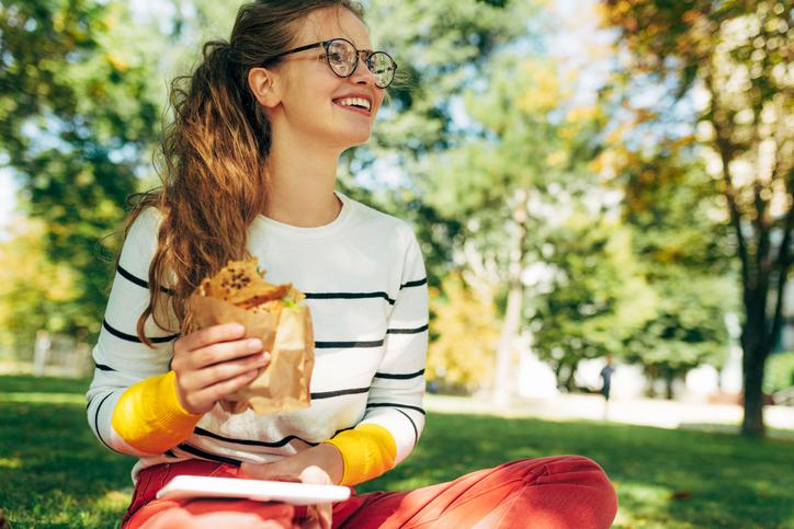Female student eating sandwich in park