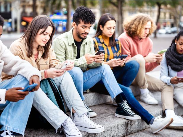 A group of Gen Z students gaze at their phones 