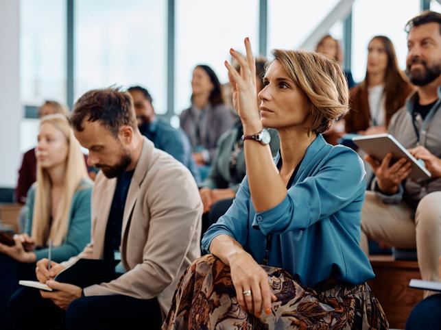 Engaged female student in lecture raising hand