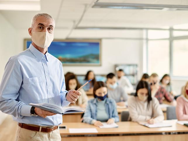 A masked teacher leads a class