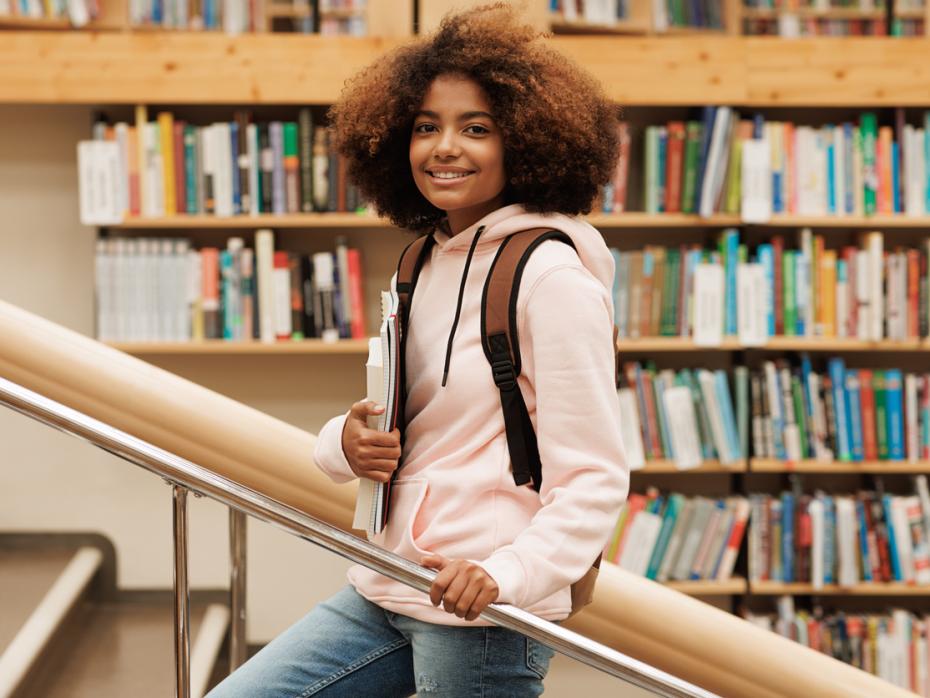 Young student standign on a staircase in a library