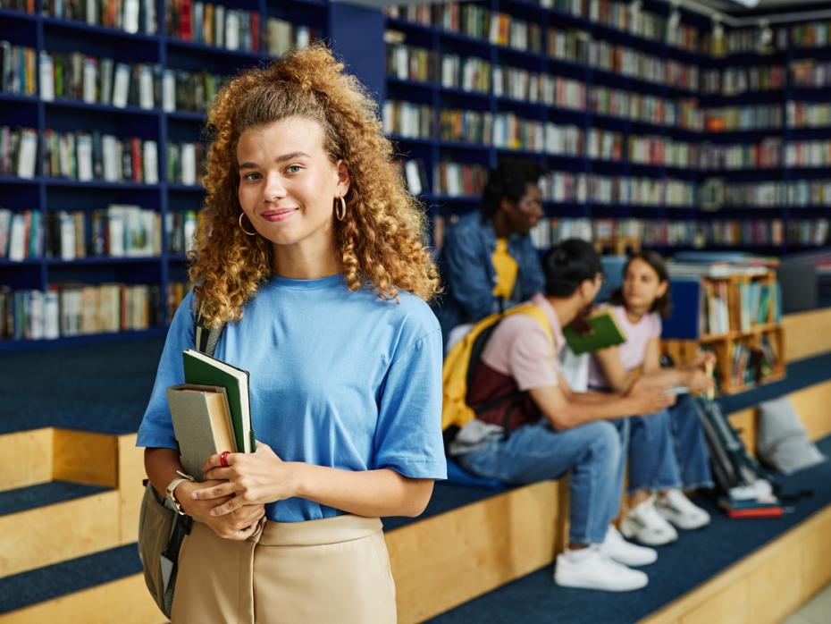 Female student smiling at the camera in a library