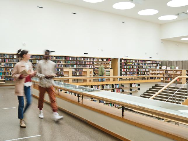 Two students walk around a well-stocked library