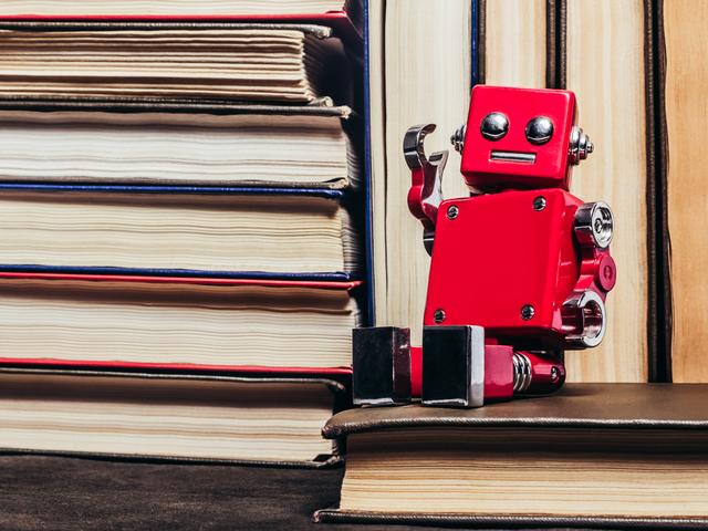 A red toy robot sits on a pile of books