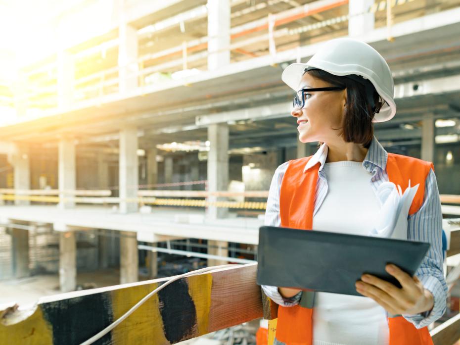 Female construction worker surveying a building