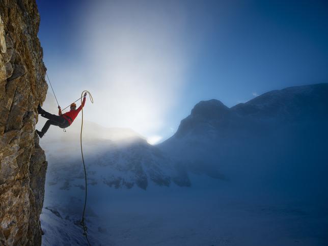 A mountain climber hangs off the side of a cliff