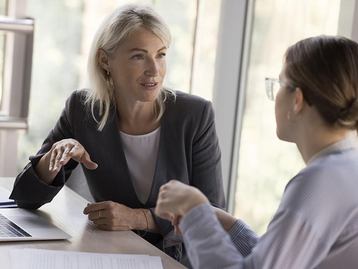 Older woman talking to young woman in a professional setting, mentoring