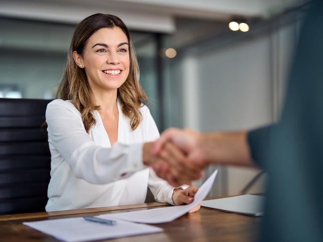 A young woman shakes hands over a desk