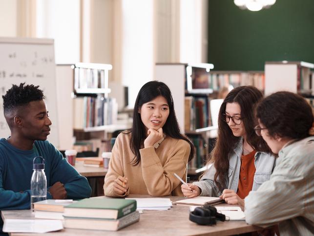 A group of students converse over a table