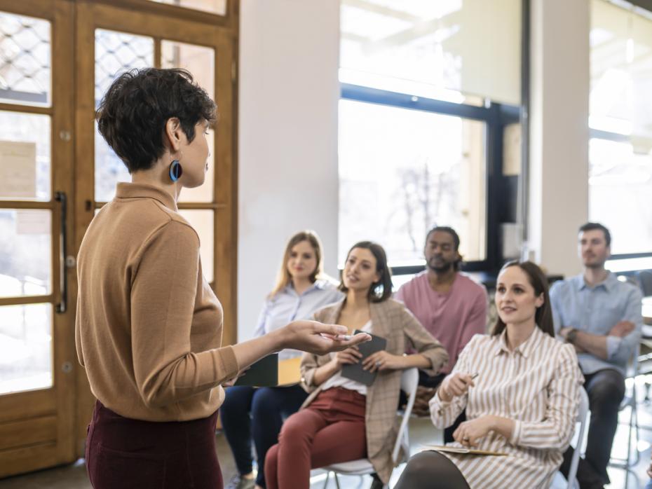 A teacher giving a lecture to a diverse class full of students