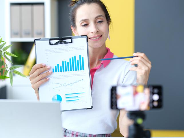 A woman holds up a bar chart to an iPhone camera