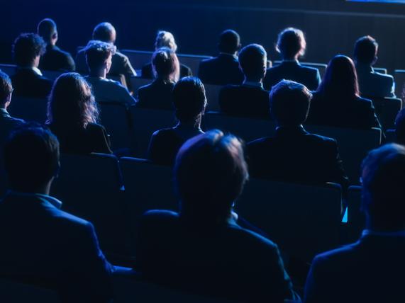 An audience in a darkened lecture hall