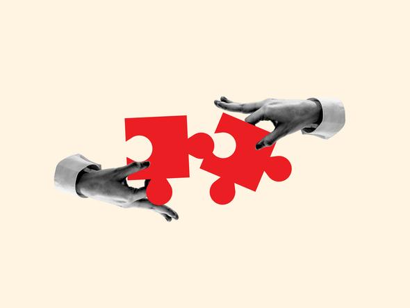 Two hands fit jigsaw puzzle pieces together