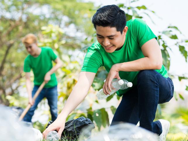 A man in a green t-shirt collects plastic bottles