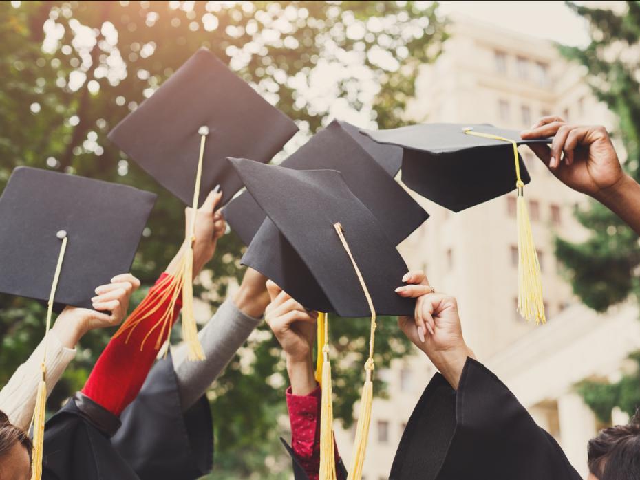 Students holding their graduation caps in the air