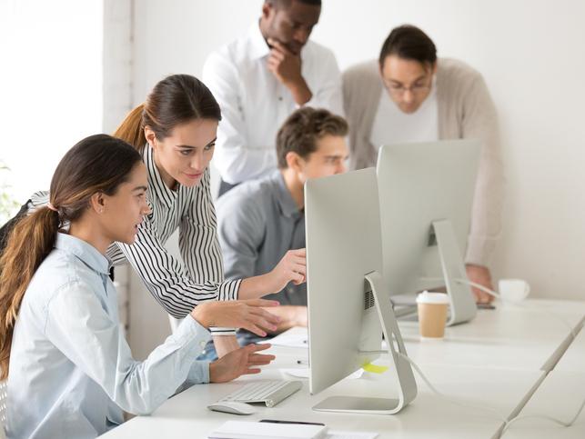 A group of people work around a computer