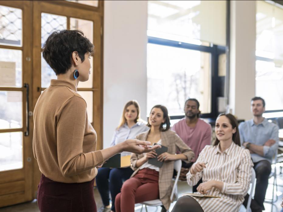 Female lecturer speaking to students at the front of class