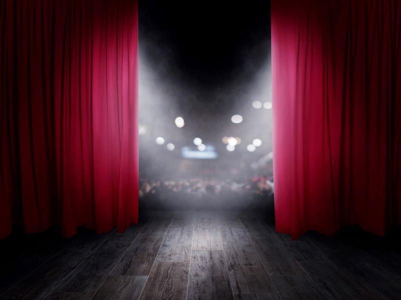 Image of the red curtains opening at the start of a theatre performance