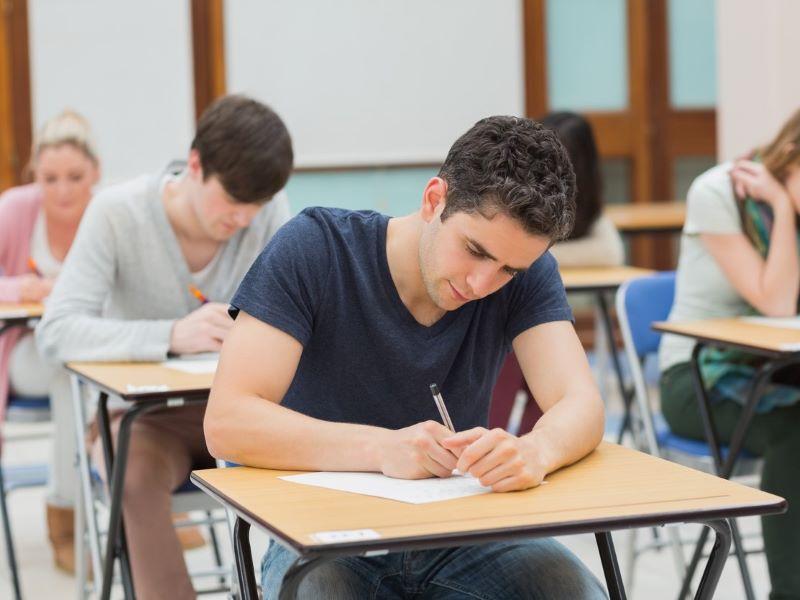 Students sit in a traditional written exam