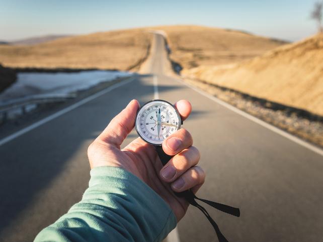 Hand holding a compass in open road