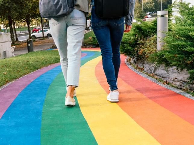 two young women walk up a rainbow-coloured footpath