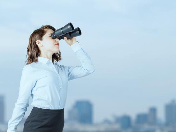 Young woman looks to horizon with binoculars