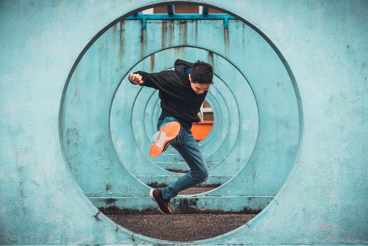Young Asian man jumping through circular obstacles