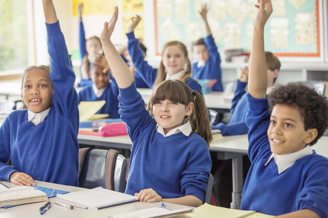 Primary school children with raised hands