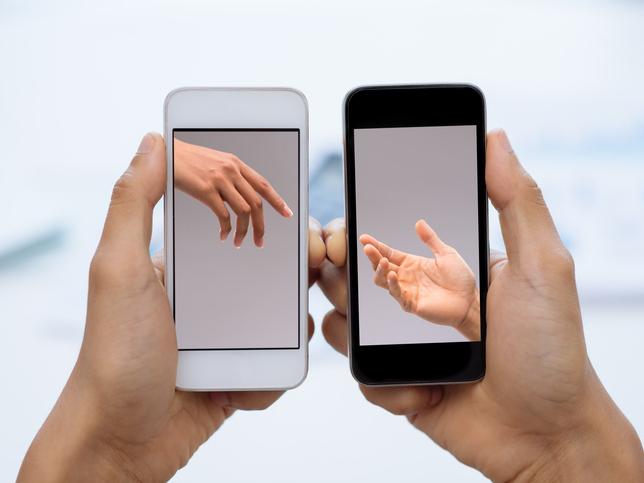 two mobile phones showing images of hands, digital communication