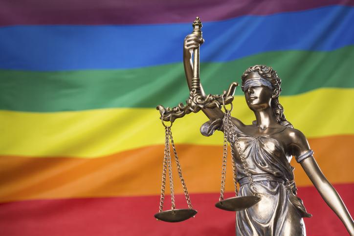 Statue of blindfolded Justice against the gay LGBT rights rainbow flag 