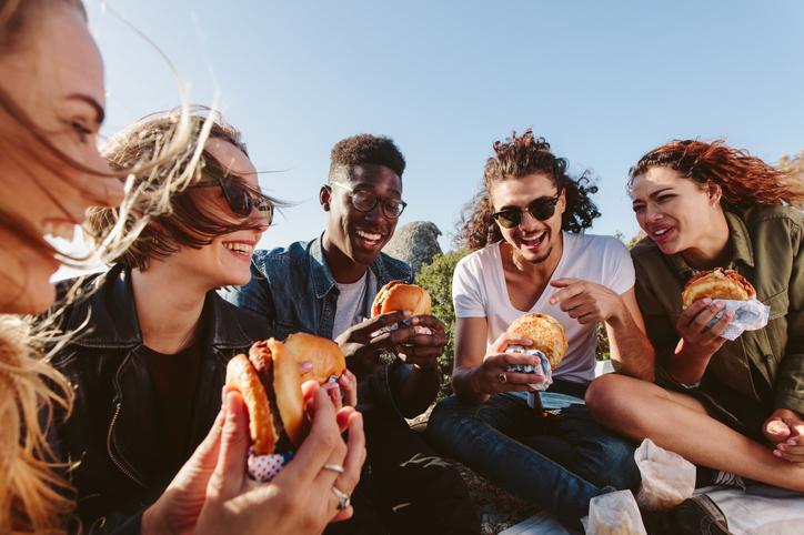 multiracial group of students eating burgers outside