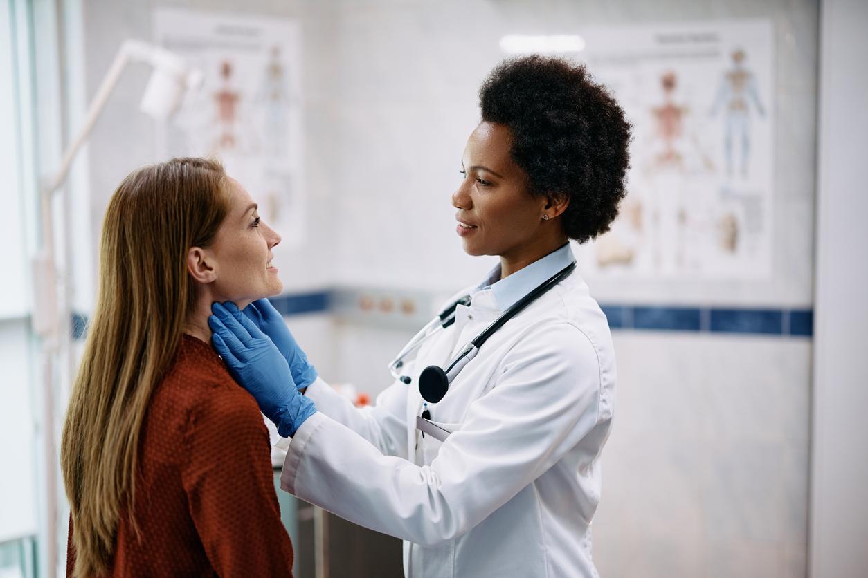 Female doctor checks a woman's thyroid