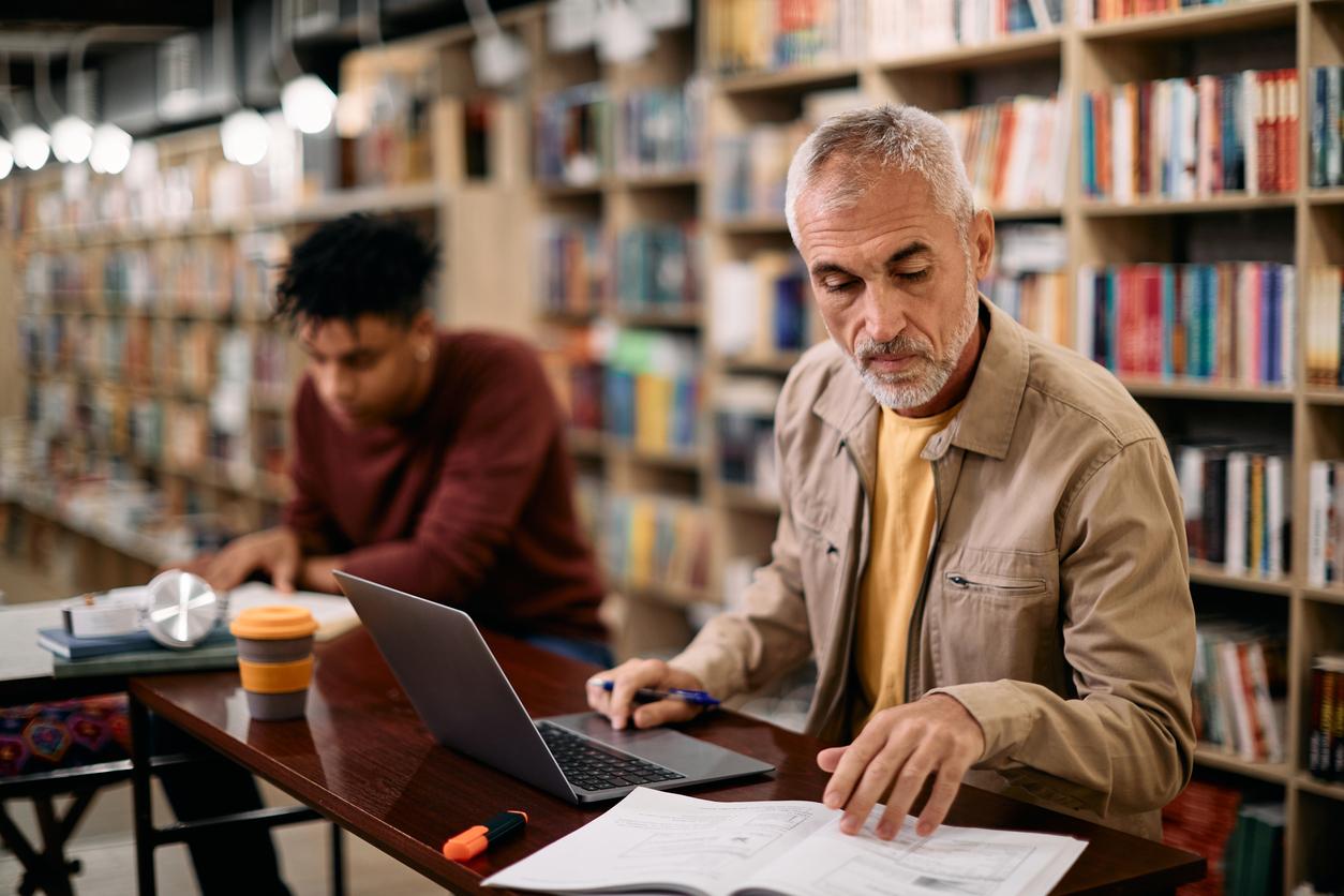 A middle aged man studying in a library